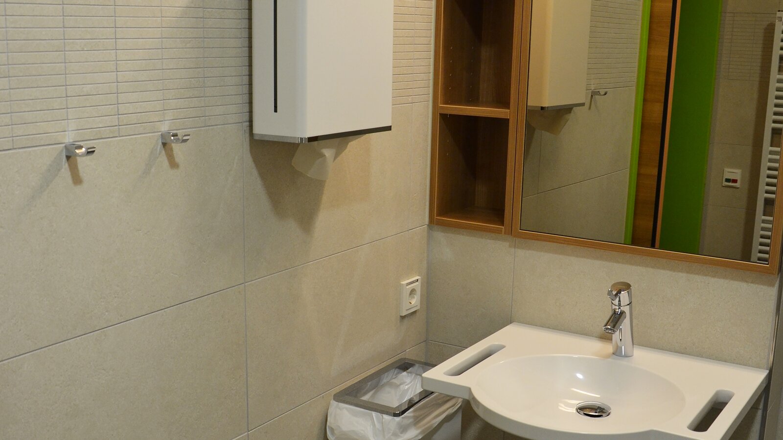 Bathroom equipped with paper towel dispenser, hygiene waste bin and a washbasin System 800