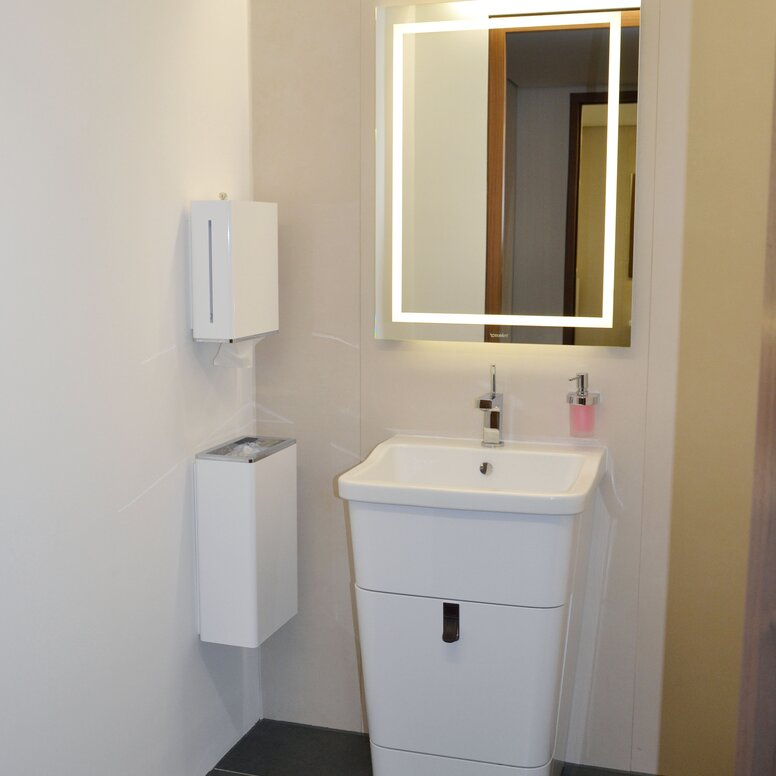 Bathroom equipped with soap dispenser, hygiene waste garbage can, mirror and paper towel dispenser